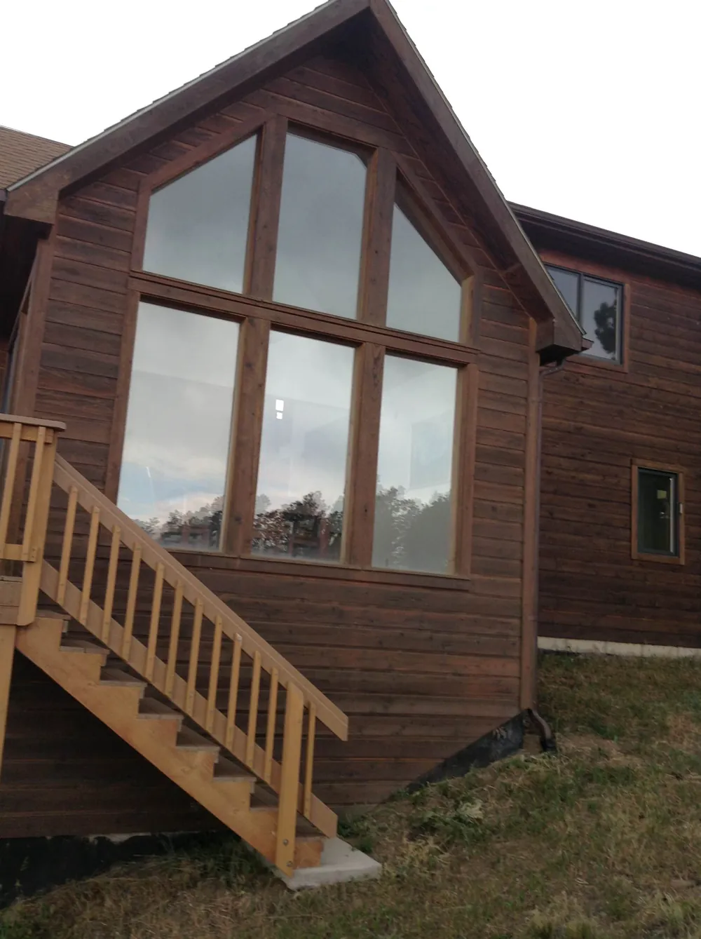 Mountain home with stained cedar siding and a tall window gable