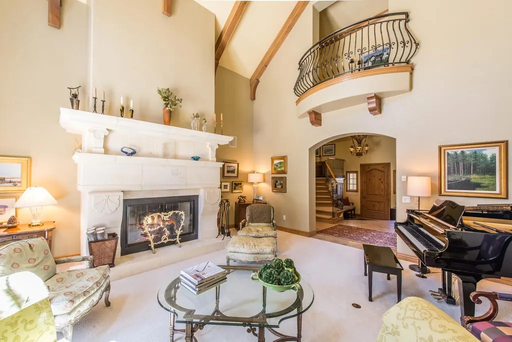 Two-story living room with a painted fireplace and balcony